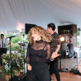 Passionate female singer performing with live band at elegant outdoor wedding in Stowe, Vermont.