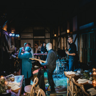 Live band performing at rustic barn wedding reception with warm lights and wooden décor.