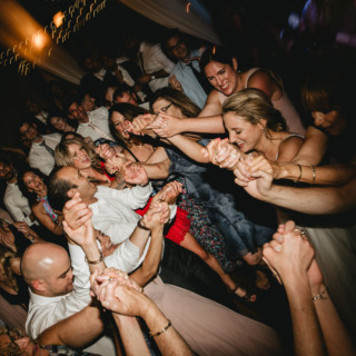 Guests dancing joyfully in a warm, lively circle at a Valley View Farm wedding celebration.