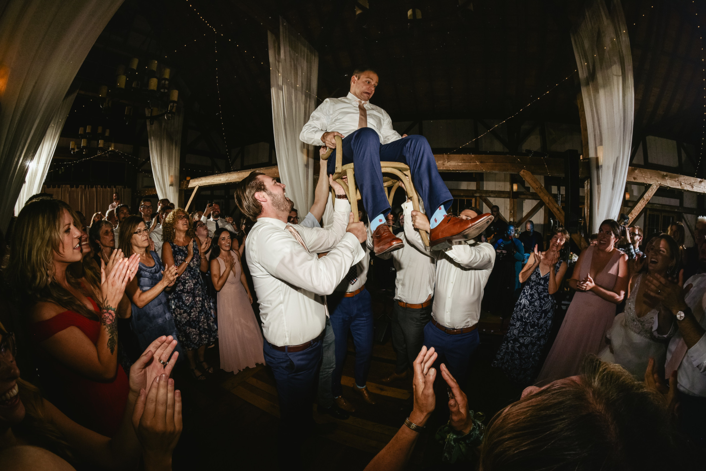 Groom lifted on chair during lively Valley View Farm wedding celebration in Haydenville, Massachusetts.