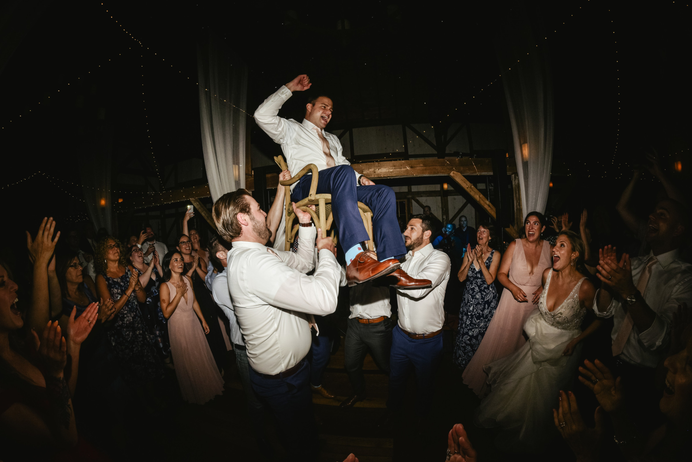 Groom lifted on a chair during joyful Valley View Farm wedding celebration in Haydenville, MA.