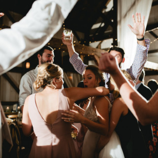 Bride and guests dancing joyfully under warm string lights at a rustic Valley View Farm wedding.