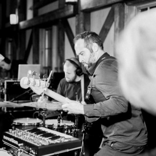 Black-and-white photo of a bassist and drummer performing live in an intimate music venue.