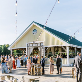 Guests enjoy a rustic outdoor wedding reception beside a yellow barn at Valley View Farm.