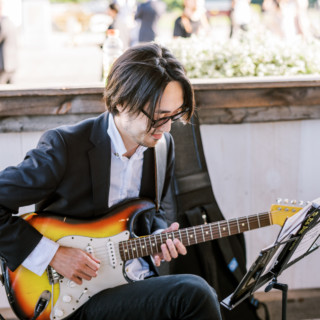 Guitarist performing on sunburst electric guitar at elegant outdoor wedding reception.