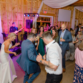 Bride and guests dancing at rustic barn wedding reception in Sebago, Maine