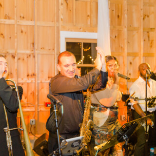 Live band performing joyfully at rustic wooden wedding venue in Sebago, Maine.
