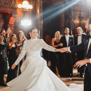 Newlyweds share their first dance in an elegant, warmly lit Boston Public Library ballroom.