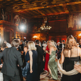 Elegant wedding reception at Boston Public Library with guests dancing under ornate chandeliers.