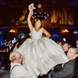 Bride lifted in joyful celebration at elegant Boston Public Library wedding reception.