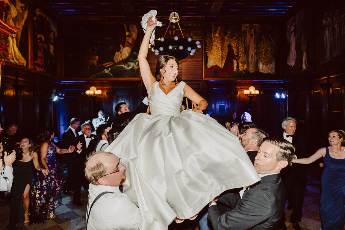 Bride lifted in joyful celebration at elegant Boston Public Library wedding reception.