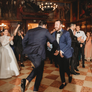 Two grooms dancing joyfully at elegant Boston Public Library wedding reception.