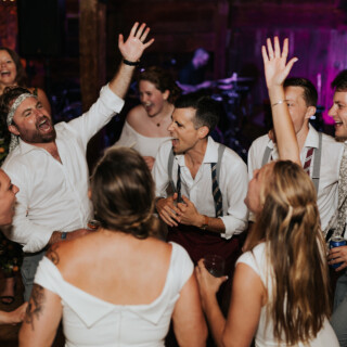 Guests singing and dancing joyfully during a rustic wedding celebration at Cunningham Farm in Maine.