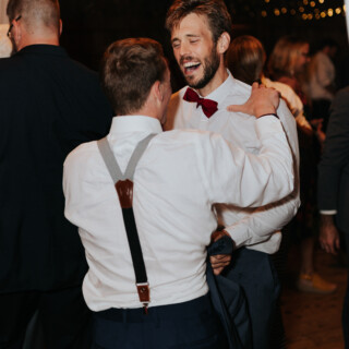 Two friends laughing and dancing at a rustic wedding reception in New Gloucester, Maine.