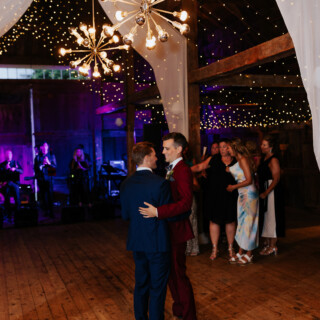 Two grooms share their first dance in a romantic, rustic barn wedding at Cunningham Farm, Maine.