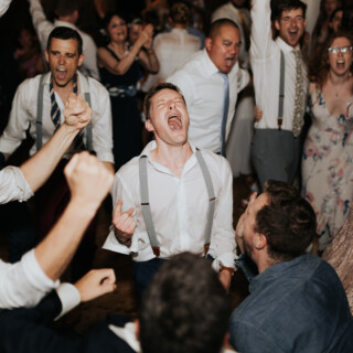 Guests cheer and dance joyfully at a lively Cunningham Farm wedding in New Gloucester, Maine.
