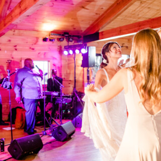 Bride dancing joyfully with bridesmaids at rustic Tourterelle Restaurant wedding in Vermont.