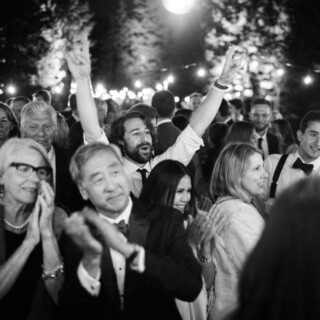 Joyful black-and-white wedding celebration under string lights at Yellowstone Club in Big Sky, Montana.