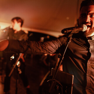 Male singer performing passionately on stage under warm dramatic lighting during a live music event.