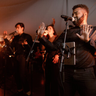 Passionate live band performance with soulful singers under warm golden stage lighting.