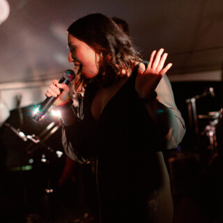 Female singer performing live on stage under warm lighting, expressing emotion through music.