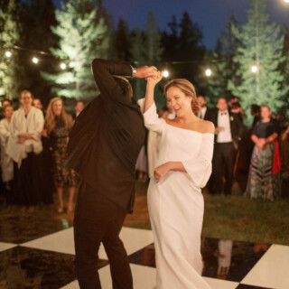 Bride and groom share a romantic first dance under string lights at Yellowstone Club wedding.
