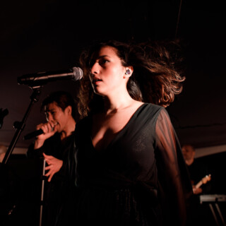 Female lead singer performing live with band under warm stage lights in Big Sky, Montana.