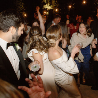 Elegant outdoor wedding reception with bride and guests dancing under warm string lights in Montana.