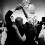 Elderly couple dancing joyfully at Nantucket wedding surrounded by guests and warm pendant lighting.