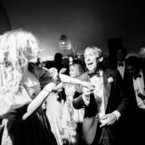 Black-and-white wedding guests dancing joyfully at Nantucket celebration under soft glowing lights.