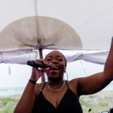 Joyful singer performing under a white beach tent at a coastal Nantucket wedding celebration.