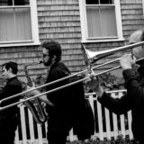 Black and white photo of three brass musicians performing outside a Nantucket home.