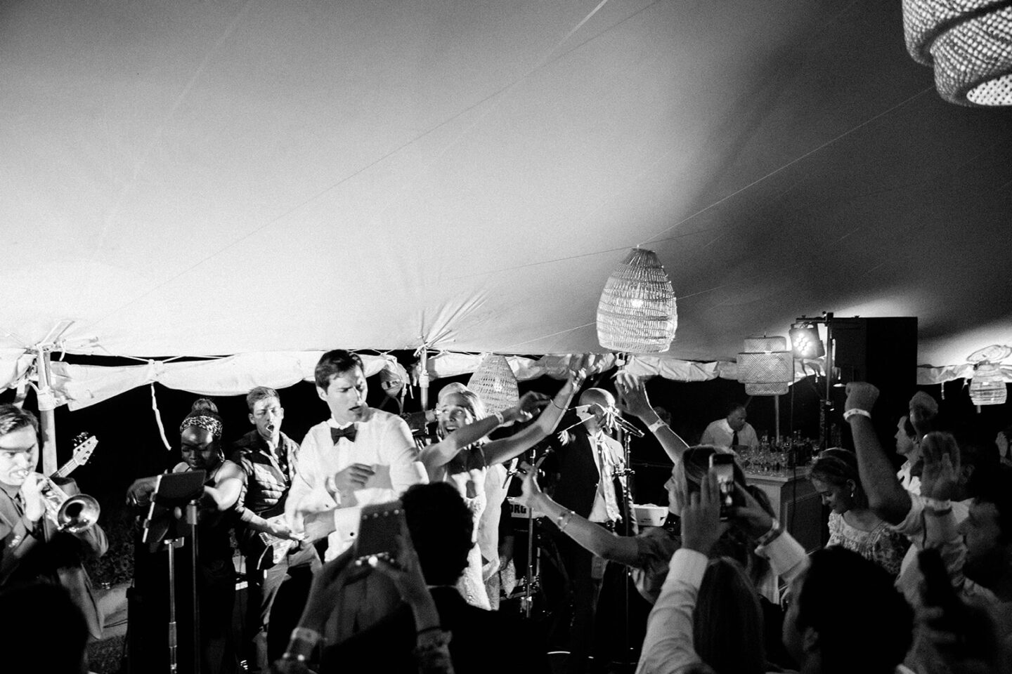 Black and white photo of three brass musicians performing outside a Nantucket home.