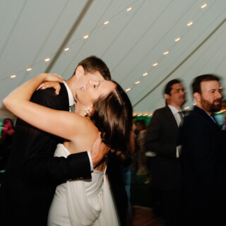 Bride and groom share a romantic first dance under string lights at Vermont wedding reception.