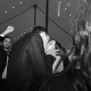 Bride and groom sharing a joyful embrace under string lights at a Vermont wedding reception.