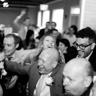 Black-and-white photo of joyful wedding guests celebrating on Thompson Island in Boston.
