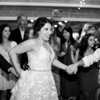 Bride laughing and dancing with guests during joyful black-and-white Thompson Island wedding celebration.