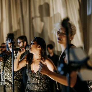 Female singer performing with live band under warm stage lights at Bar Harbor Club event.