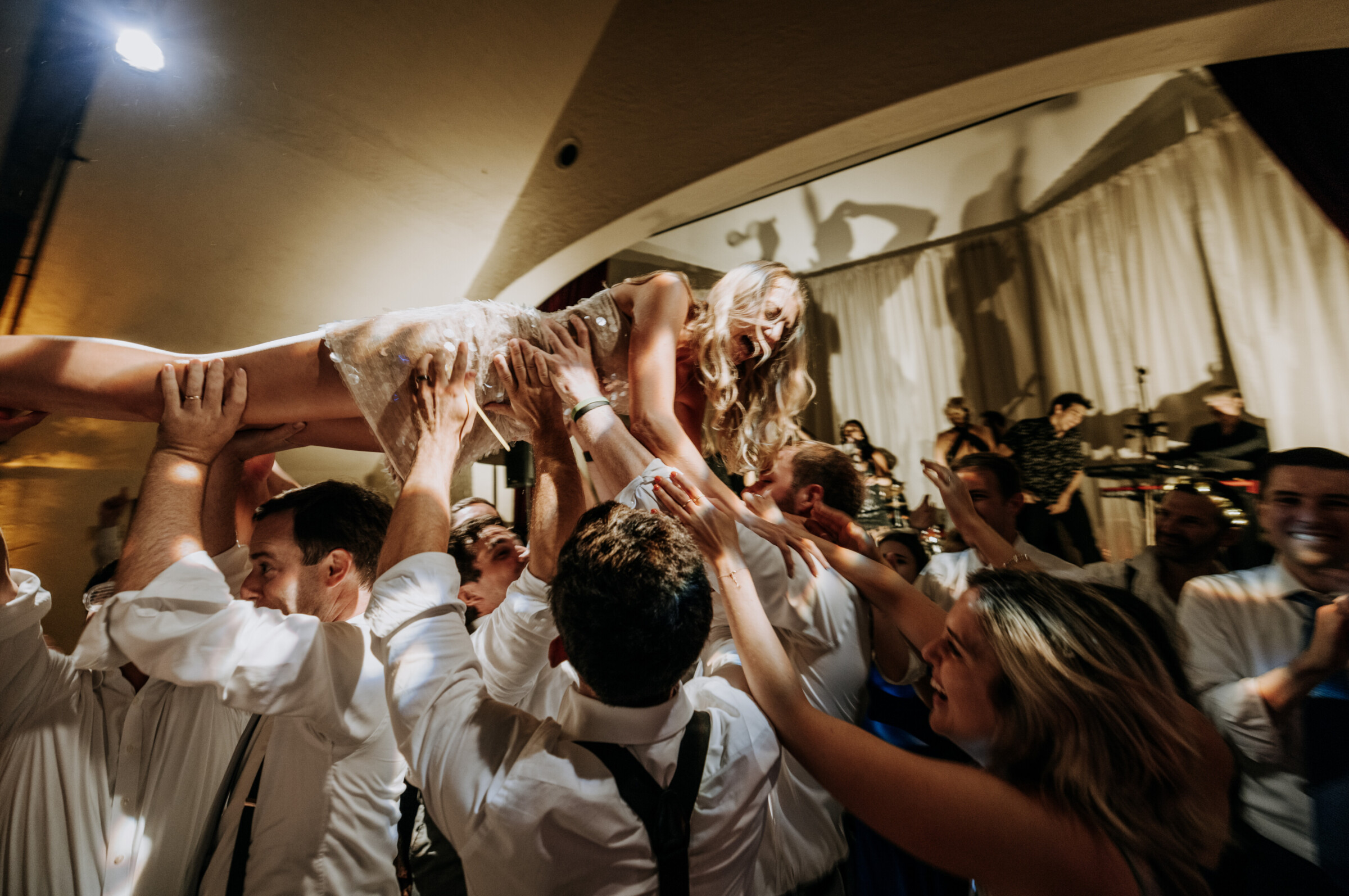Bride lifted joyfully by guests during lively wedding celebration at Bar Harbor Club, Maine.