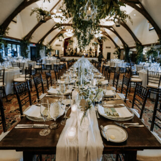 Elegant wedding reception at Bar Harbor Club with candlelit banquet table and hanging greenery.