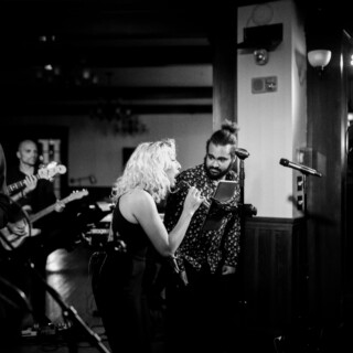 Emotional black-and-white live duet performance at an intimate music venue.