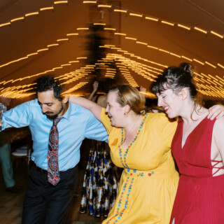 Friends dancing joyfully under wedding string lights at Mount Hope Farm in Bristol, Rhode Island.