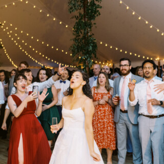 Bride laughing with guests under glowing fairy lights at Mount Hope Farm wedding in Bristol.