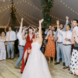 Bride dancing and celebrating with guests under string lights at Mount Hope Farm wedding.