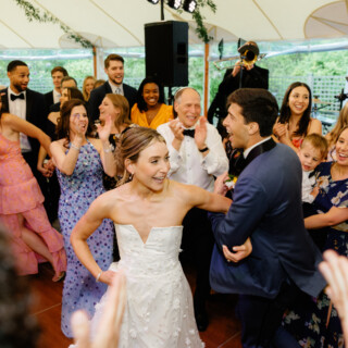 Bride and groom dancing joyfully at Willowdale Estate wedding surrounded by cheering guests and live music.