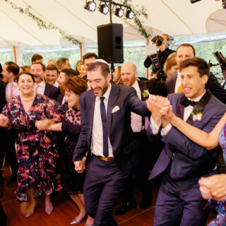 Two grooms dancing joyfully with guests at Willowdale Estate wedding in Topsfield, Massachusetts.