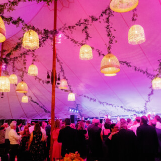 Guests dancing under warm pendant lights and magenta uplighting at a romantic Willowdale Estate wedding.