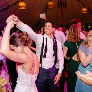 Bride and groom dancing joyfully with guests under glowing lights at Willowdale Estate wedding.