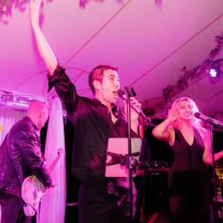 Energetic live band performing under pink and purple lights at a Willowdale Estate wedding reception.