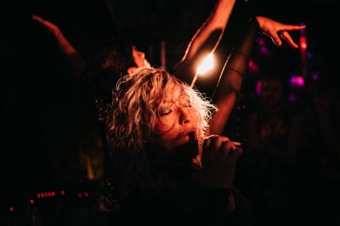 Female singer performing passionately under warm stage lights with emotional energy and artistic expression.